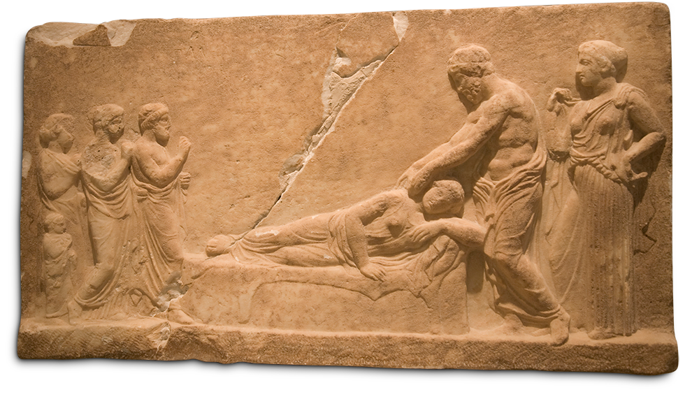 Large slab of stone carved with six figures in bas relief. A large crack runs diagonally through the slab.